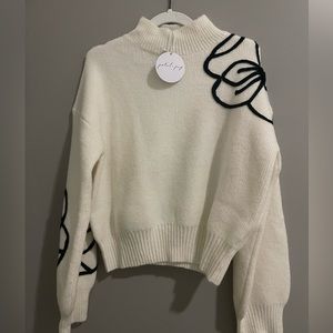 White sweater with black flower detail